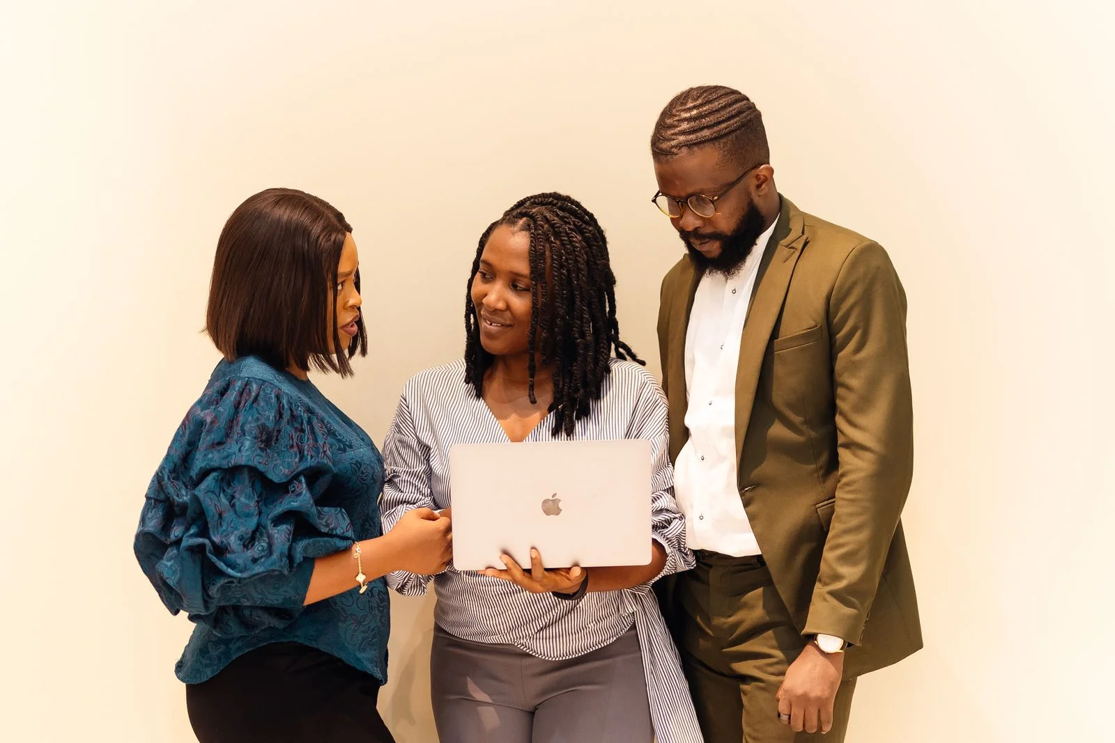 Two women and a colleague discuss work beside an open laptop in Lagos